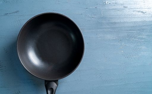 A top view of a black frying pan on a blue wooden table