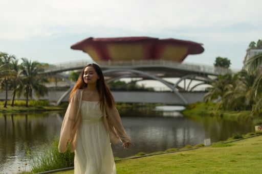 A shallow focus shot of an Asian female wearing a white dress by a river