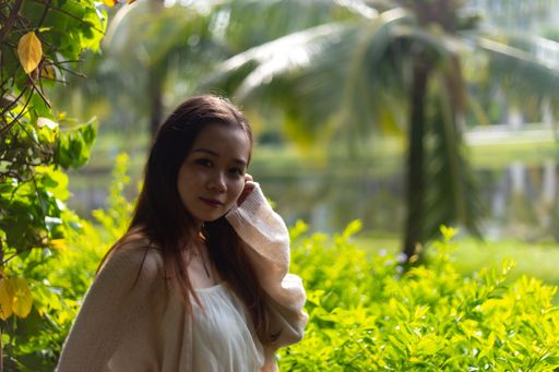 A shallow focus shot of an Asian female wearing a white dress in nature