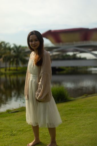 A vertical shallow focus shot of a barefoot Asian female wearing a white dress on the streets