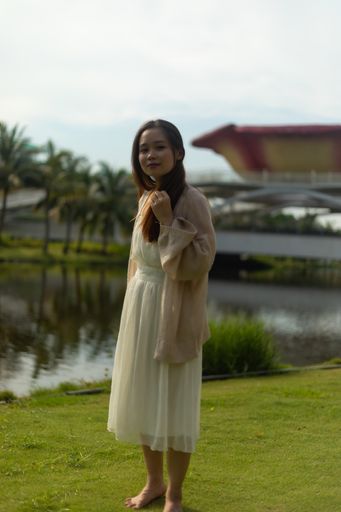 A vertical shallow focus shot of a barefoot Asian female wearing a white dress on the streets