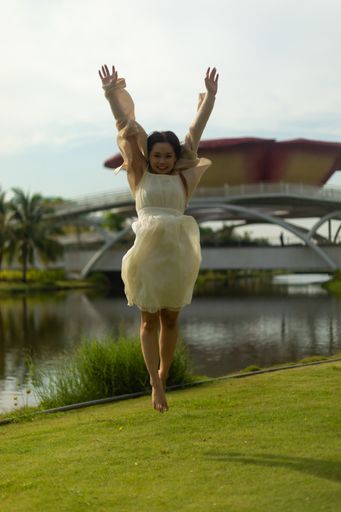 An amazing shot of a happy woman jumping in the park her hands up