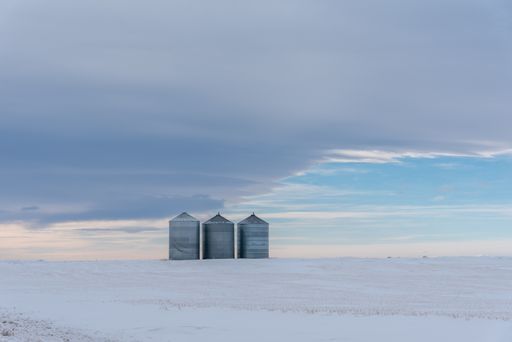 A beautiful view of grain bins in winter with cloudy sky in the background
