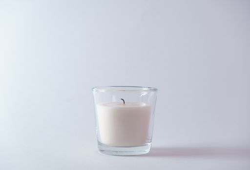 A closeup of a scented candle against a white wall