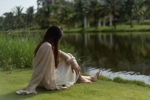 A shallow focus shot of a young beautiful woman sitting in the grass at the park