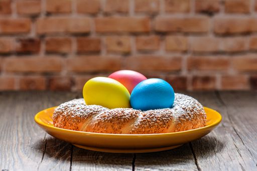 A plate of colorful festive eggs and easter sweet baking in the blurred brick wall background