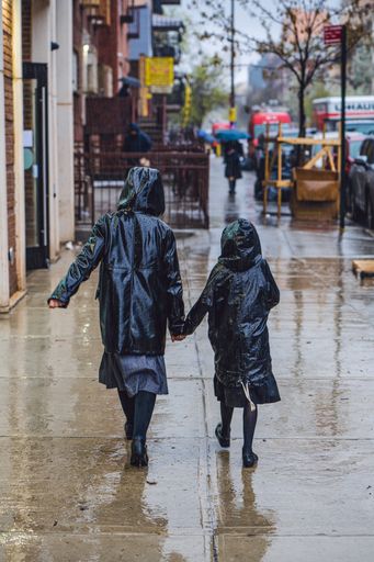 A vertical shot of girls in raincoats walking in the rain in Brooklyn
