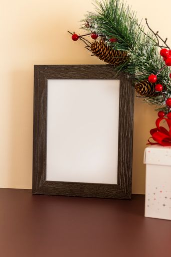 A blank wooden frame with decorative Christmas tree branch and present