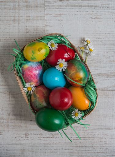 A high angle shot of colorful easter eggs in a basket on a wooden surface