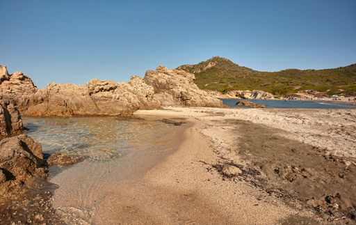 Beautiful aerial view of the Cala Sa Figu beach in Sardinia with its crystal clear sea that meets the colored sand