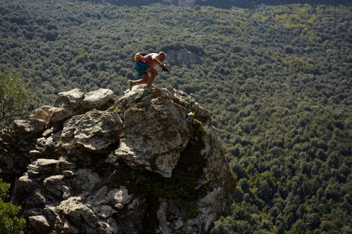Young naturalistic photographer as he climbs the summit of a mountain in the center of Sardinia and jumps to the summit