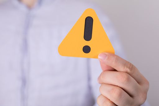 A man holding a yellow triangular warning sign