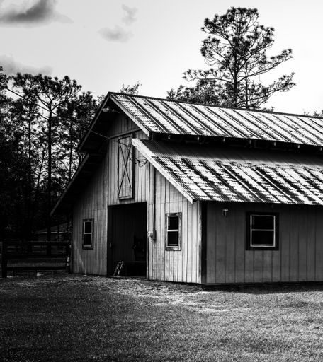 A grayscale shot of a wooden barn on a field