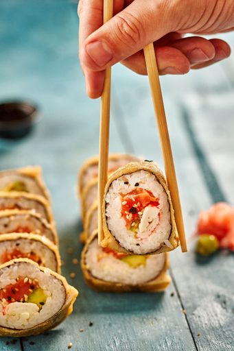 A vertical shot of sushi rolls and chopsticks