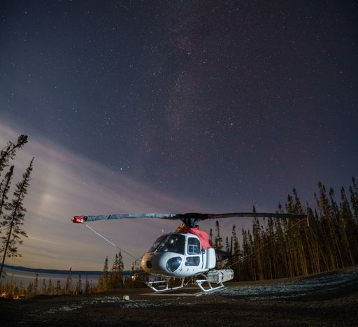 A helicopter in a forest under a starry night sky