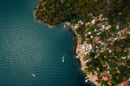 An aerial shot of houses on the coast, and boats sailing in Lake Atitlan in Guatemala, Central America