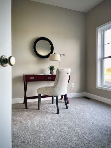 A vertical shot of a modern interior with a brown desk, white chair, and a round mirror
