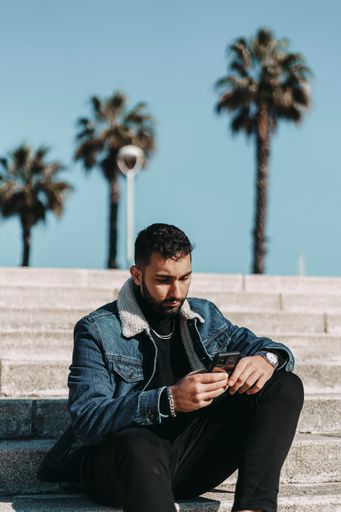 A young handsome Caucasian male posing at a beach resort sitting on the stairs