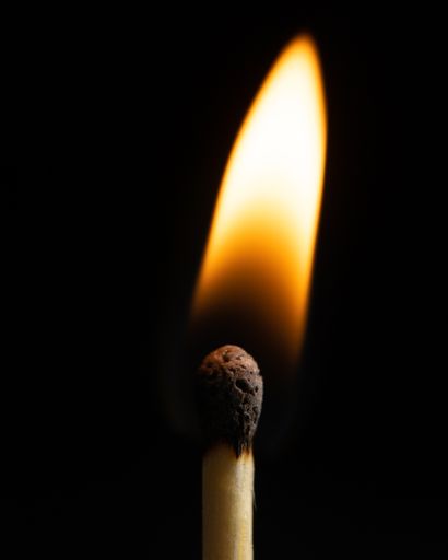 A closeup shot of a burning match on a black background