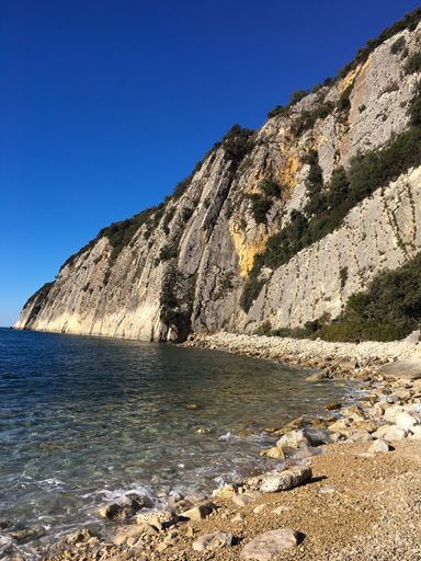 A vertical shot of a cliff and a beach with a blue sky