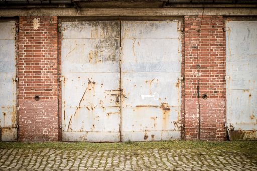 An old rusty weathered garage gate with brick walls