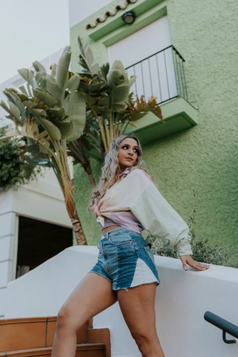 A Caucasian blonde pretty girl posing in the park under the sun with a summer outfit