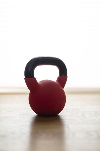 A closeup shot of a red kettlebell for doing exercises at home