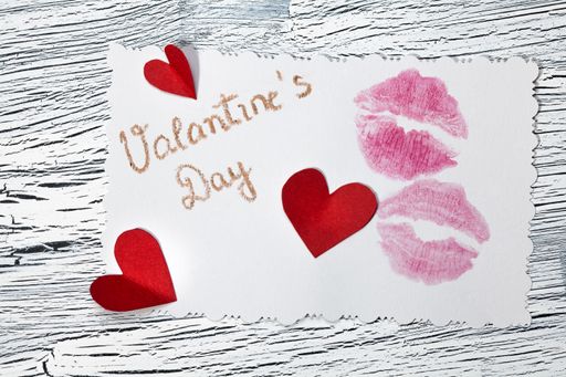 Red paper hearts on a white paper with Valentine's day writing