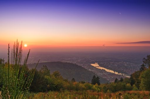 A scenic view of a colorful sky at the sunset over the cityscape with a river