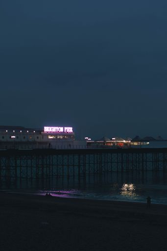 A vertical shot of theBrighton Palace Pier surrounded by lights at night in the UK