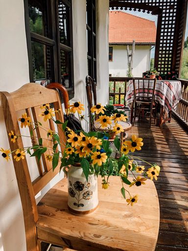 A vertical shot of yellow flowers in a pot on a vintage terrace in Agapia Museum, Romania