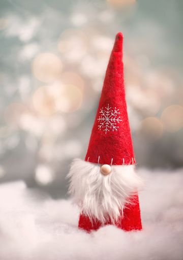 Christmas gnome greeting card with bokeh lights and snow, winter season, gift on the sledge