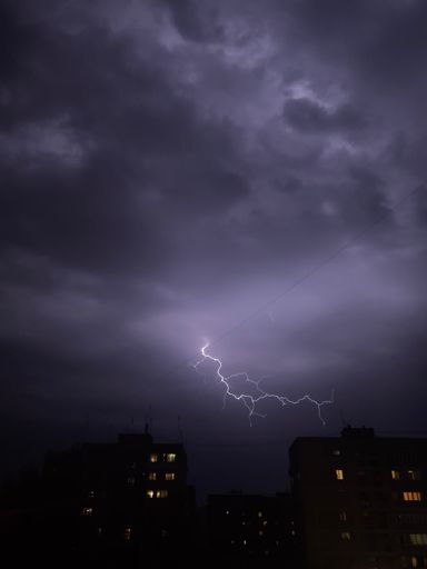 A vertical shot of a cityscape under dark storm clouds and lightning in Armenia