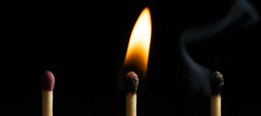 A closeup of three matches of an extinguished match next to a burning one isolated on the black background