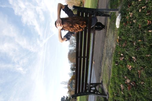 Woman with long brown hair sitting on the bench at the park