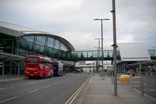 Buses parked next to the Terminal 2 building at Dublin Airport, Ireland. Modern architecture. Curved glass building with walkways above the street.