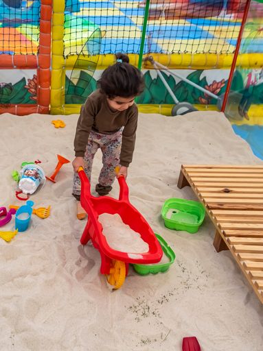 An adorable Caucasian little girl playing with the toys on the sand in the playground