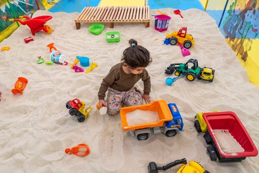An adorable Caucasian little girl playing with the toys on the sand in the playground