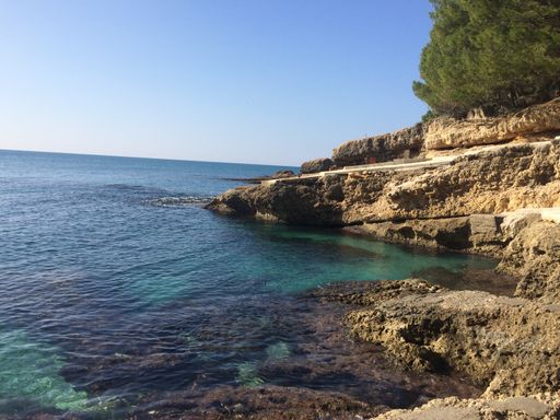 A beautiful view of the rocky cliffs and a pathway going into the calm and blue ocean