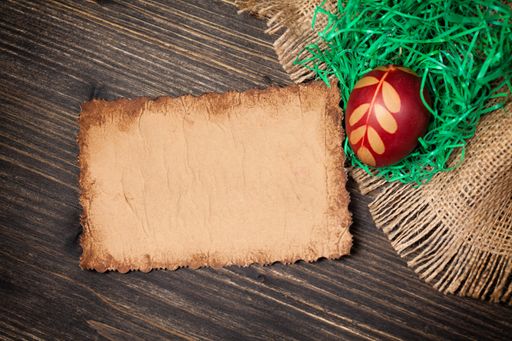 A top view of an Easter egg and old vintage paper card on a wooden surface