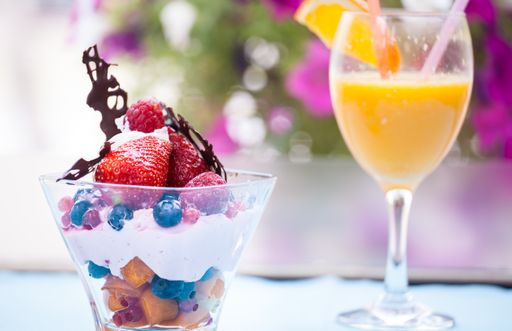 A closeup shot of vanilla ice cream with berries and fruits and a glass of orange juice