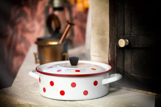 A selective focus shot of a vintage white cooking pot with red dots