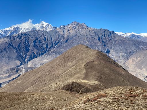 The rocky mountains with peaks covered with snow under the clear blue sky on a sunny day