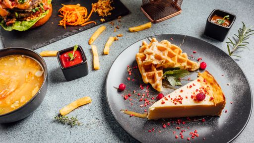 A closeup shot of cheesecake and waffles decorated with berries