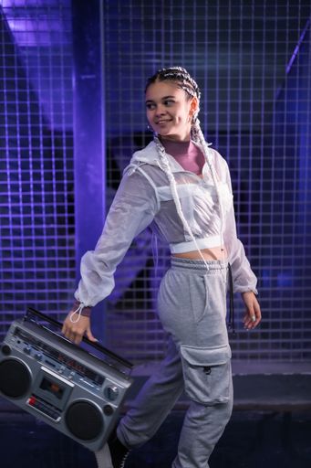 A vertical shot of a pretty Caucasian lady with piercings, braids, and a boombox - in the 80s style