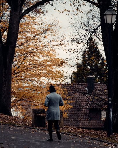 A vertical shot of the man walking down the street in autumn.
