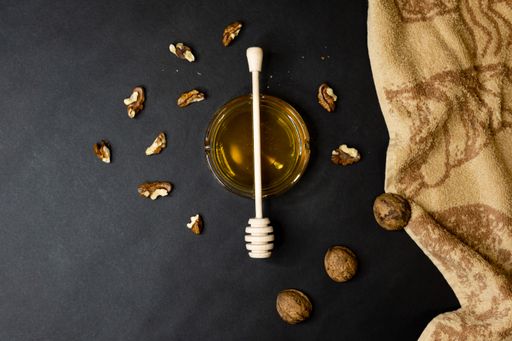A top view of honey and walnuts on a black background