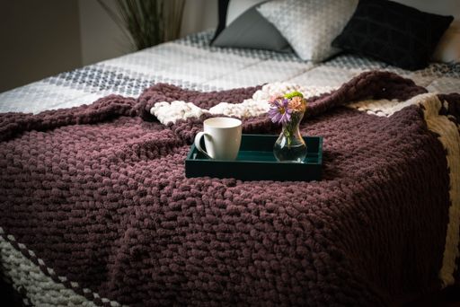 The home interior of cozy bedroom in modern design with pillows and soft custom made chunky blanket