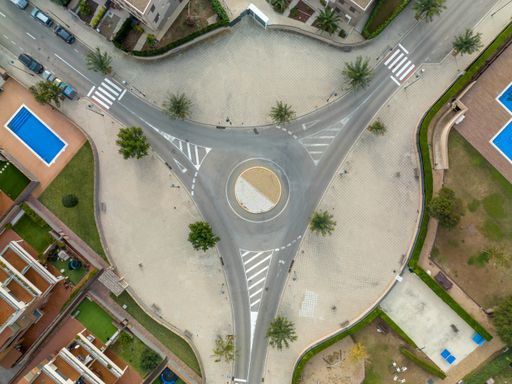 An aerial view of a roundabout with cars parked on the street