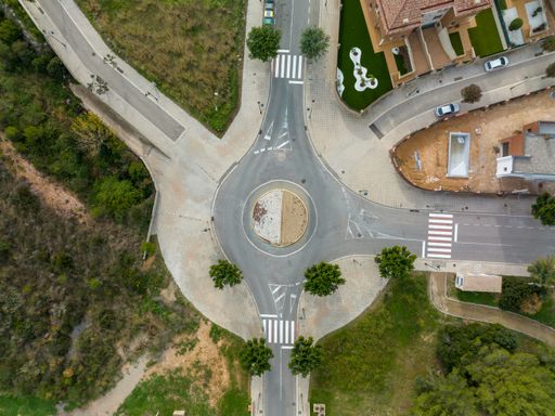 An aerial view of a roundabout with cars parked on the street and trees nearby